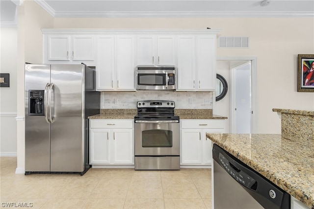 kitchen with light stone countertops, white cabinets, appliances with stainless steel finishes, and light tile floors