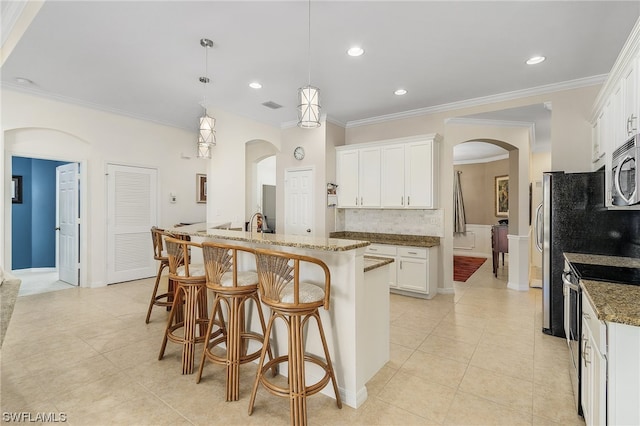 kitchen with light tile floors, hanging light fixtures, white cabinets, appliances with stainless steel finishes, and dark stone countertops