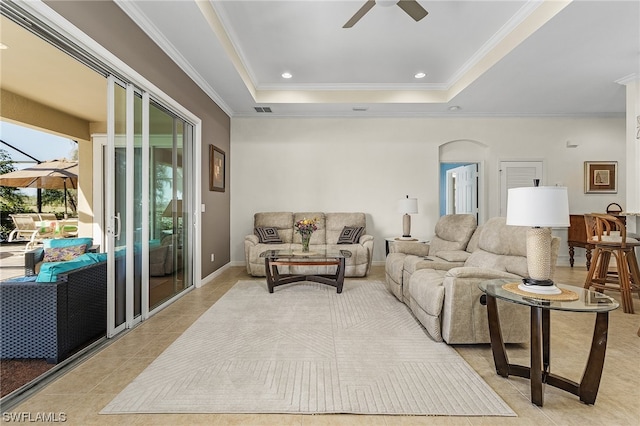 living room featuring a raised ceiling, crown molding, ceiling fan, and light tile floors