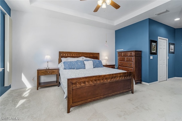 bedroom featuring light carpet, a raised ceiling, and ceiling fan