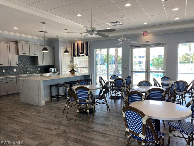 dining space featuring sink, a paneled ceiling, dark hardwood / wood-style floors, ceiling fan, and ornamental molding