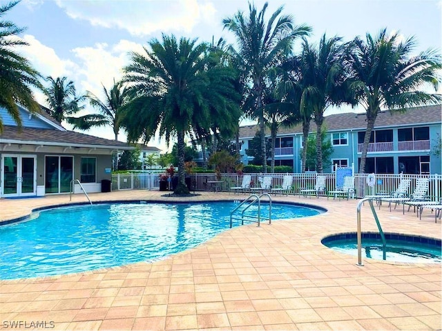 pool featuring a hot tub, fence, and a patio