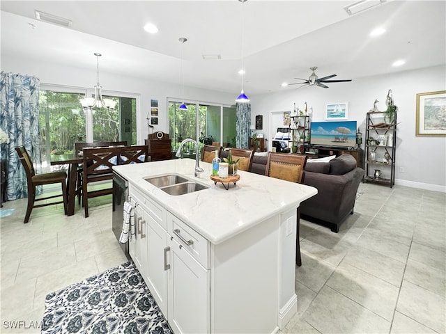 kitchen featuring light stone countertops, sink, an island with sink, ceiling fan, and pendant lighting