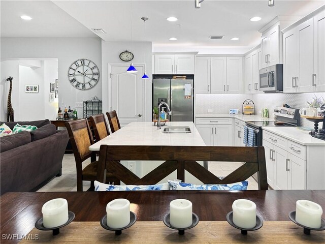 kitchen with hanging light fixtures, sink, appliances with stainless steel finishes, and white cabinets