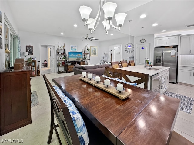 dining room featuring sink, ceiling fan with notable chandelier, and light tile patterned flooring