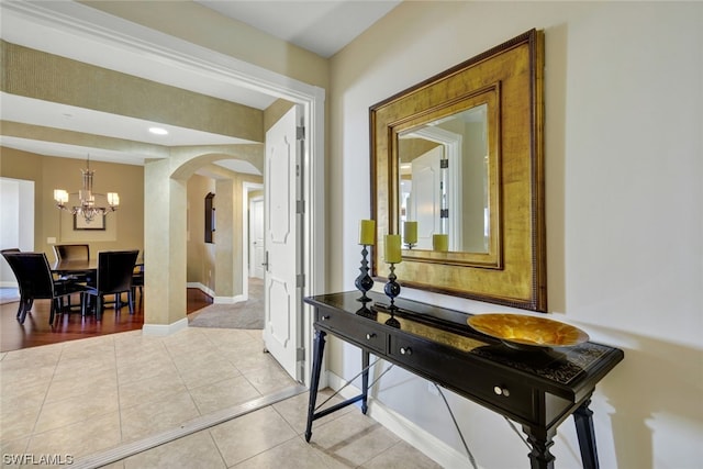 hall with light tile patterned floors and a notable chandelier