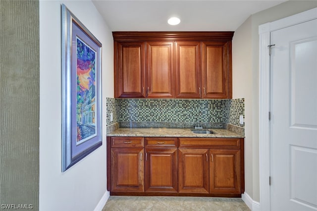 kitchen featuring sink, light stone counters, and backsplash