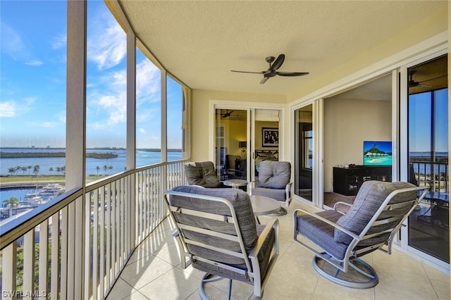 sunroom featuring ceiling fan and a water view