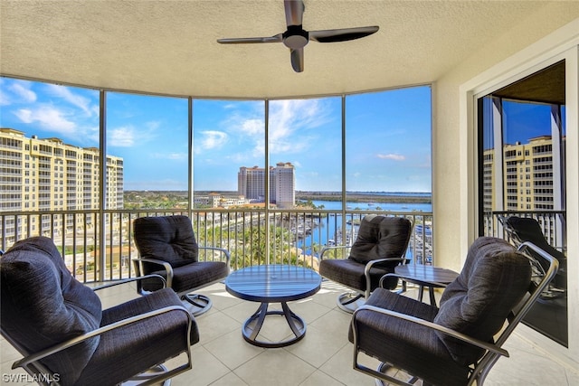 sunroom with ceiling fan and a water view