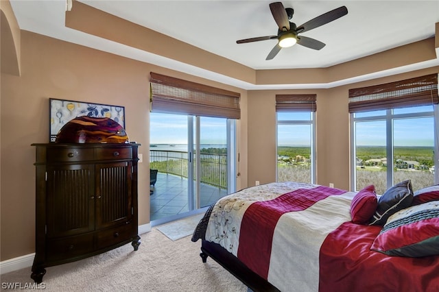 carpeted bedroom featuring access to exterior, a water view, and ceiling fan