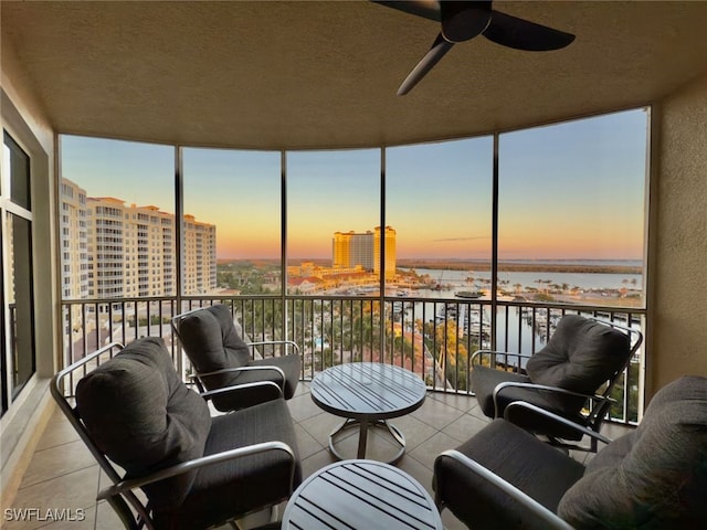 sunroom / solarium with a water view and ceiling fan