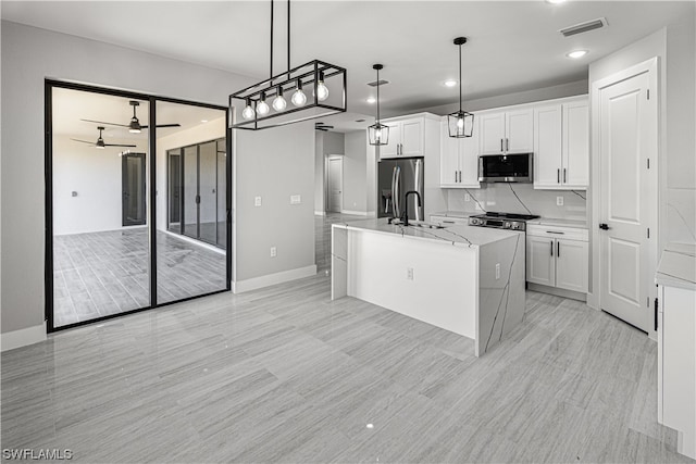 kitchen featuring stainless steel appliances, white cabinets, a center island with sink, and ceiling fan