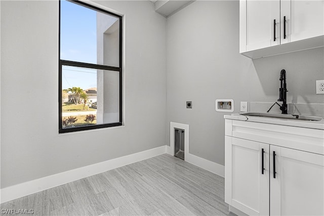 clothes washing area with washer hookup, sink, hookup for an electric dryer, cabinets, and light hardwood / wood-style floors