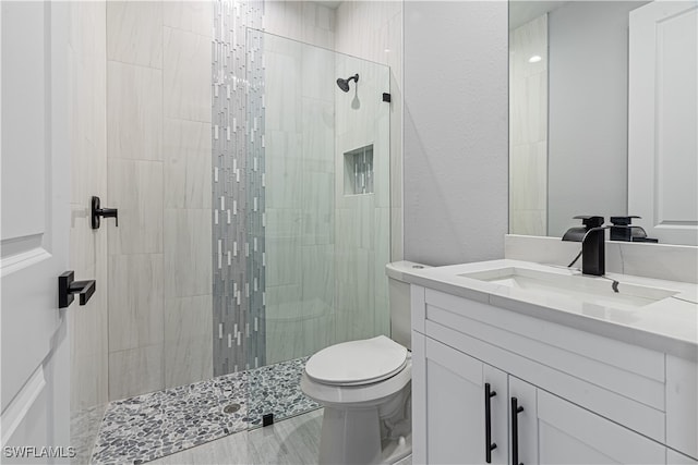 bathroom featuring a tile shower, vanity, and toilet