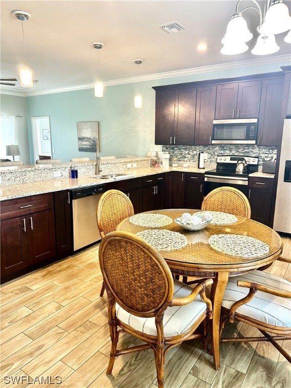 kitchen with a notable chandelier, appliances with stainless steel finishes, tasteful backsplash, and pendant lighting