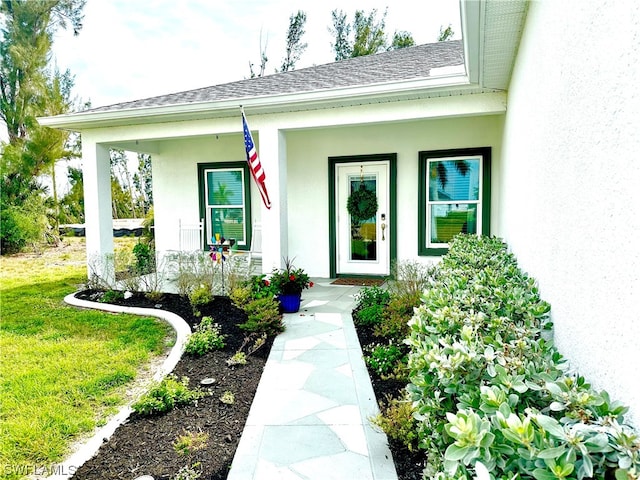 doorway to property with a porch and a lawn