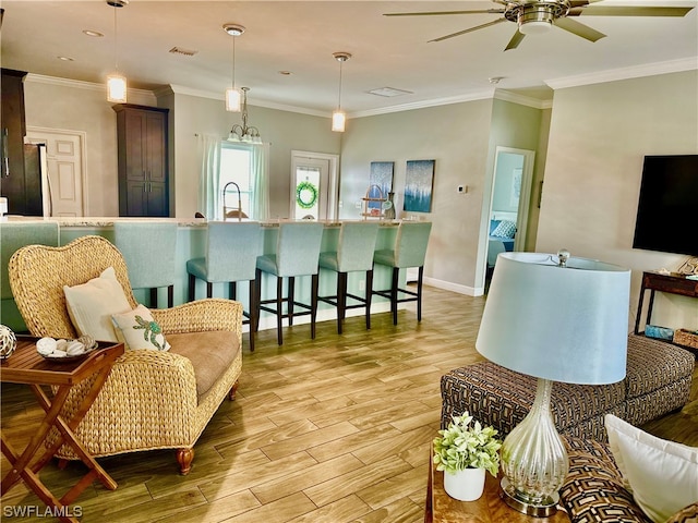 living room featuring light hardwood / wood-style flooring, ceiling fan with notable chandelier, sink, and ornamental molding