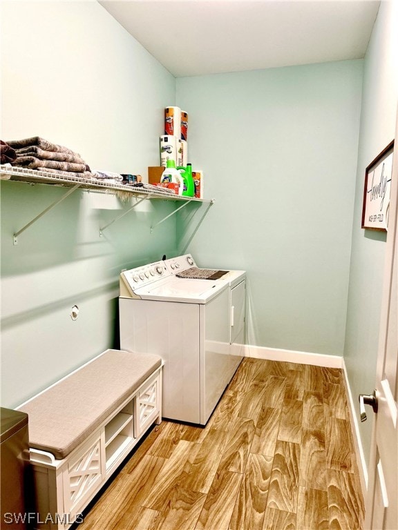 laundry room with washing machine and dryer and light wood-type flooring