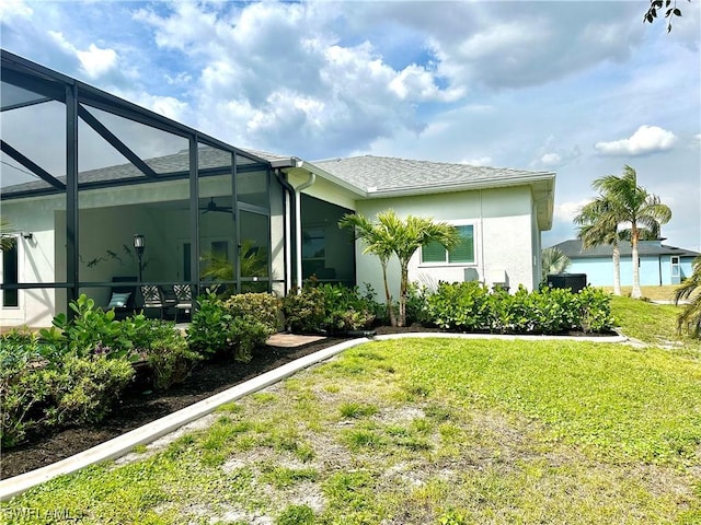 exterior space featuring a lanai, ceiling fan, and a lawn