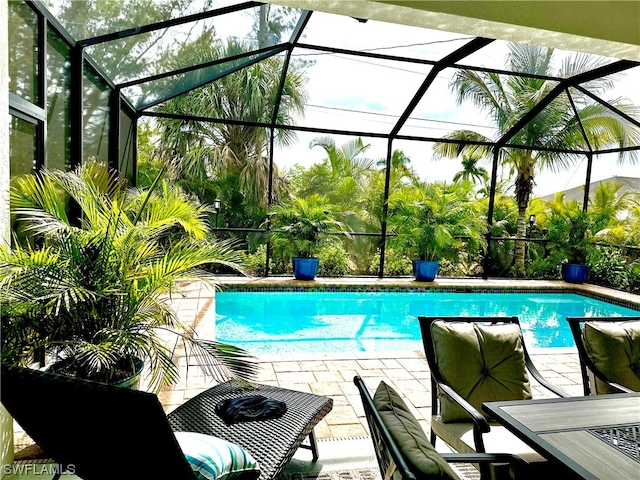 view of swimming pool featuring glass enclosure and a patio area