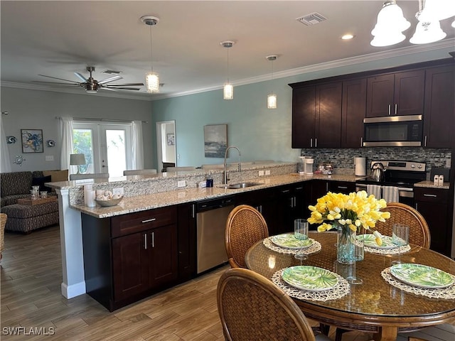 kitchen with stainless steel appliances, dark brown cabinets, sink, and pendant lighting