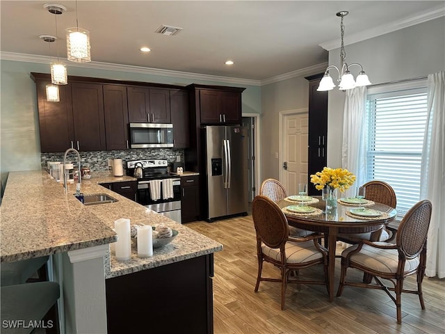 kitchen featuring appliances with stainless steel finishes, sink, pendant lighting, and kitchen peninsula