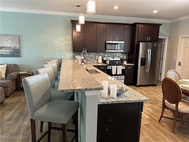 kitchen featuring appliances with stainless steel finishes, sink, backsplash, hanging light fixtures, and kitchen peninsula