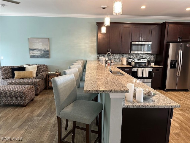 kitchen with appliances with stainless steel finishes, sink, a breakfast bar area, hanging light fixtures, and kitchen peninsula