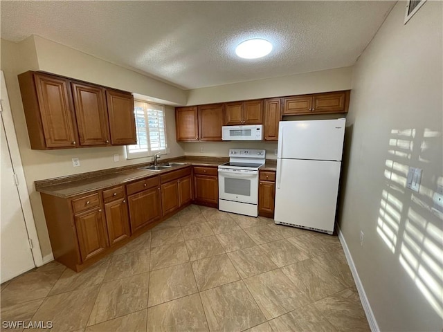 kitchen with sink, a textured ceiling, and white appliances