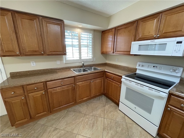 kitchen featuring sink, white appliances, light tile patterned floors, and a textured ceiling