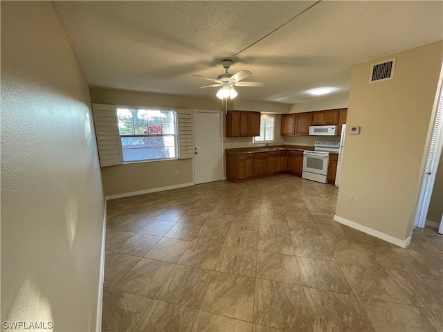 kitchen with ceiling fan, sink, a textured ceiling, and white appliances