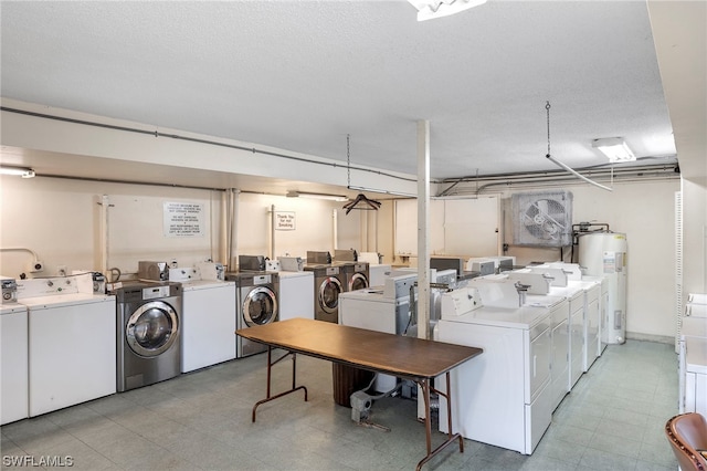 laundry room featuring electric water heater, a textured ceiling, and washer and clothes dryer