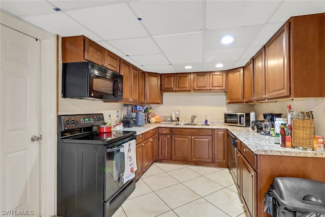 kitchen with sink, light tile patterned floors, a paneled ceiling, and black appliances