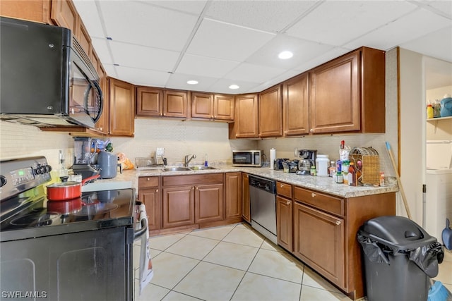 kitchen with appliances with stainless steel finishes, a paneled ceiling, light stone counters, sink, and light tile patterned flooring