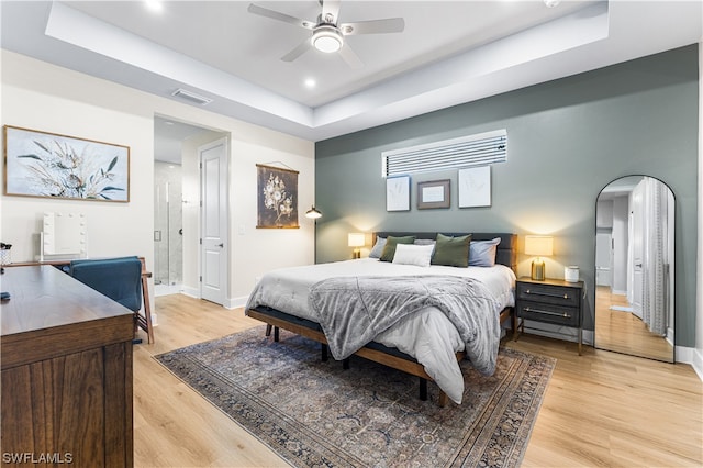 bedroom featuring a tray ceiling, ceiling fan, and light hardwood / wood-style flooring