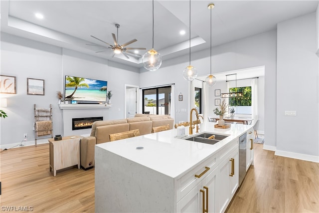 kitchen with a tray ceiling, ceiling fan, light hardwood / wood-style floors, sink, and white cabinets