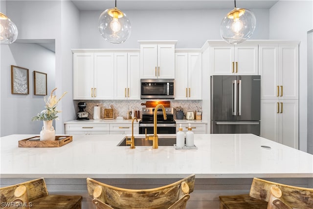 kitchen featuring appliances with stainless steel finishes, hanging light fixtures, backsplash, and a kitchen bar