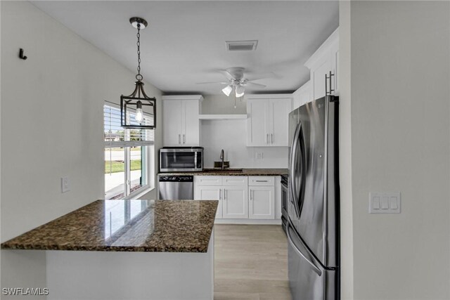 kitchen with decorative light fixtures, white cabinetry, stainless steel appliances, dark stone countertops, and sink