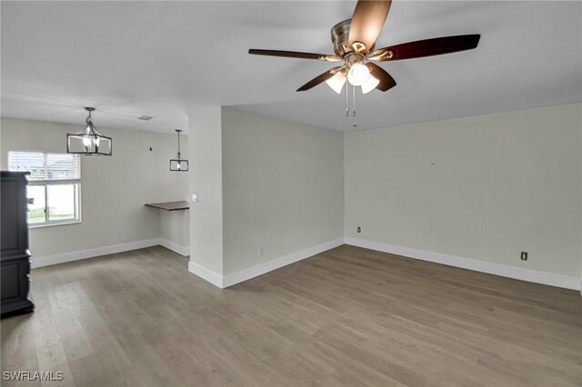 unfurnished living room featuring hardwood / wood-style flooring and ceiling fan with notable chandelier