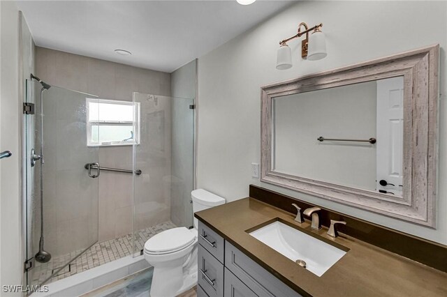 bathroom with hardwood / wood-style flooring, toilet, vanity, and a tile shower