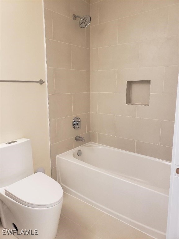 bathroom with tiled shower / bath combo and toilet