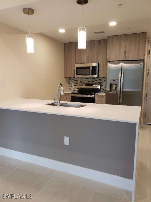 kitchen featuring light tile patterned floors, stainless steel appliances, and hanging light fixtures