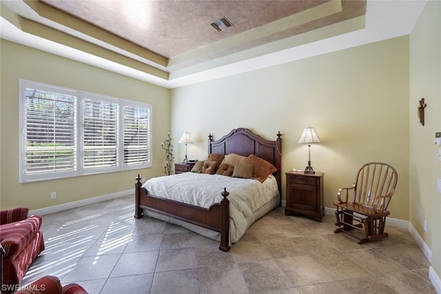 bedroom featuring light tile floors and a tray ceiling