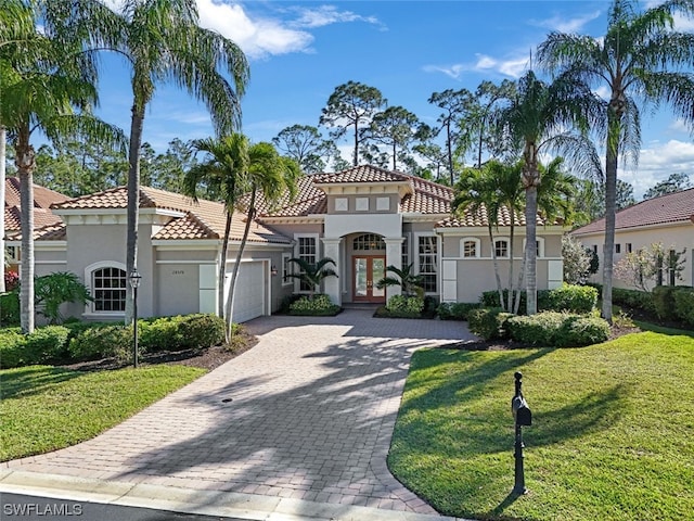 mediterranean / spanish home featuring a front lawn and a garage