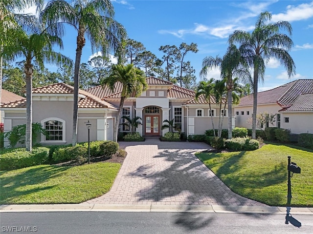 mediterranean / spanish home with a front yard and french doors