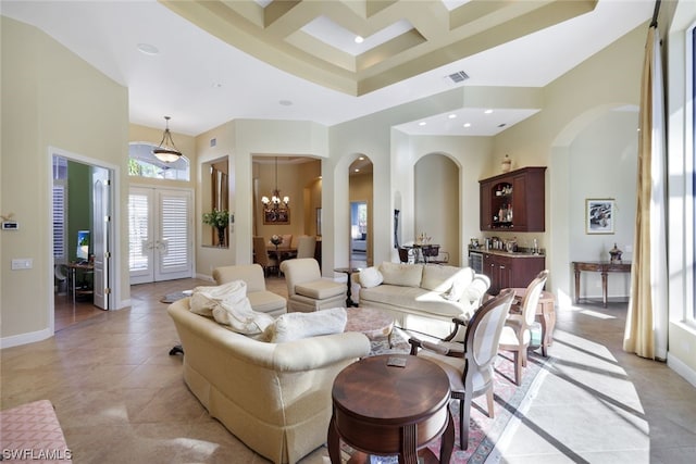 tiled living room featuring an inviting chandelier, coffered ceiling, french doors, and a towering ceiling