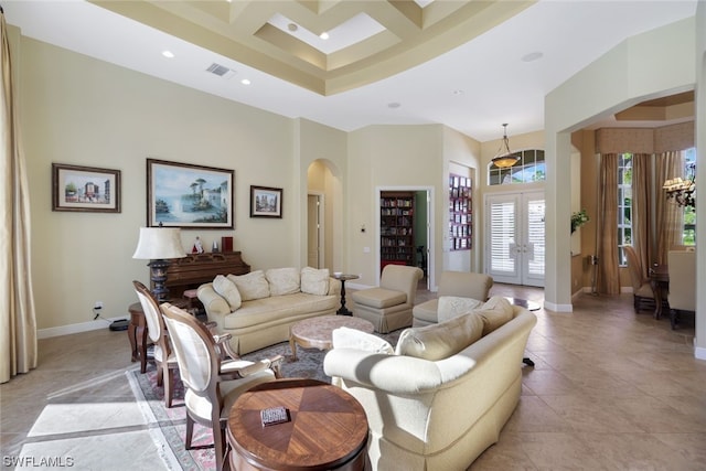 tiled living room featuring coffered ceiling, a high ceiling, a notable chandelier, and french doors