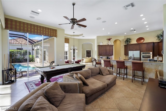 tiled living room with billiards and ceiling fan with notable chandelier