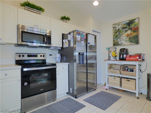 kitchen featuring appliances with stainless steel finishes, light tile patterned floors, and white cabinetry