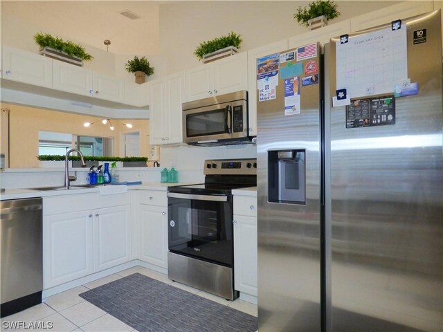 kitchen featuring appliances with stainless steel finishes, light tile patterned floors, white cabinetry, and sink